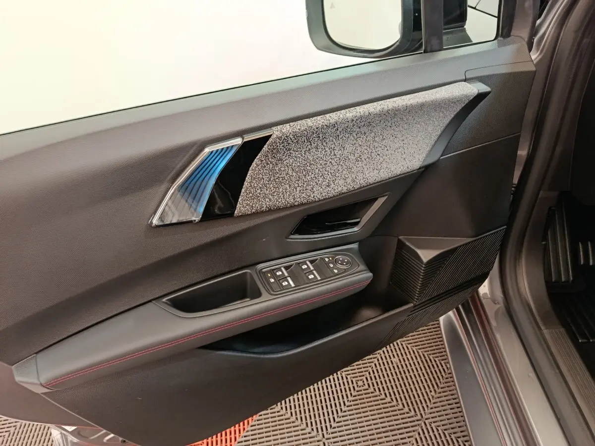 Vue intérieure côté gauche de la porte avant d’une Renault Clio gris foncé, avec commandes électriques et finition tissu gris.