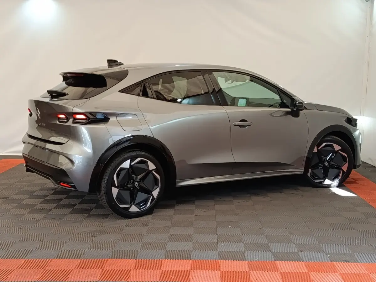 Vue de profil côté droit d'une Renault Clio Techno gris foncé avec jantes noires et feux arrière allumés.