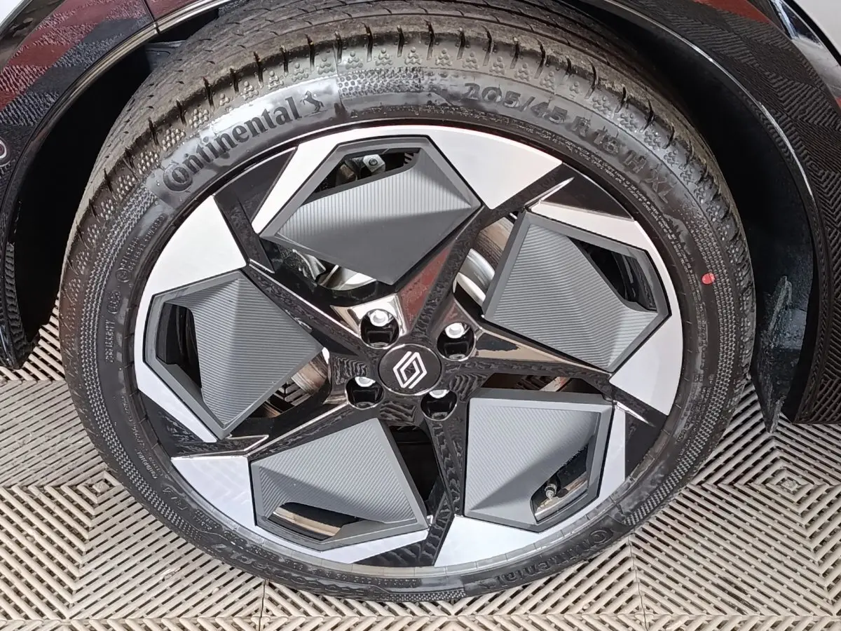Gros plan sur la roue avant droite de la Renault Clio gris foncé, jante au design géométrique noir et argent.