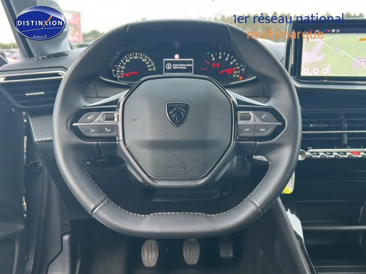 Vue centrée sur le volant cuir du Peugeot 208 1.2 100 style 2025 avec tableau de bord et écran tactile visibles.