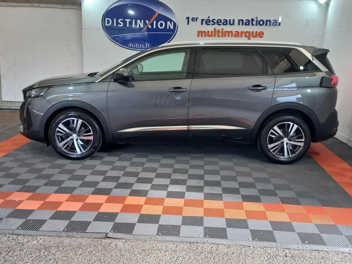 Profil droit d'un Peugeot 5008 gris foncé 2021 avec jantes alliage et toit contrasté blanc en intérieur showroom.