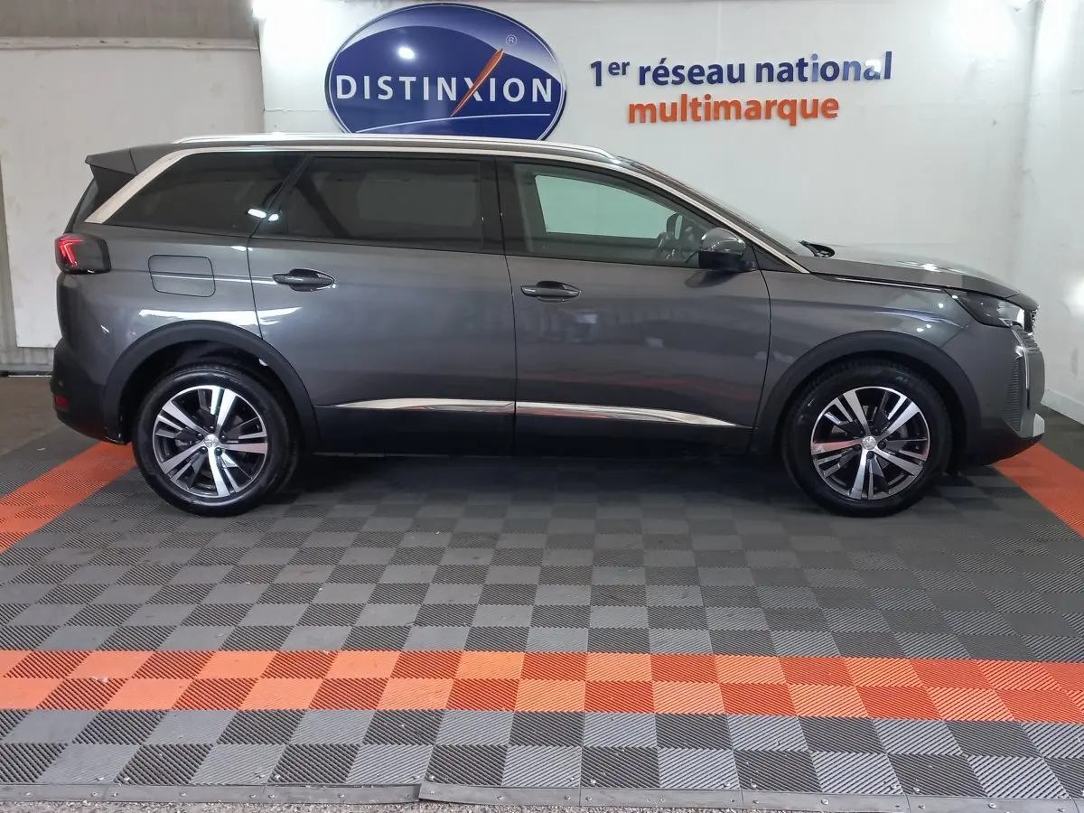 Profil droit d’un Peugeot 5008 gris foncé 2021 stationné en intérieur avec jantes alliage et vitres teintées.