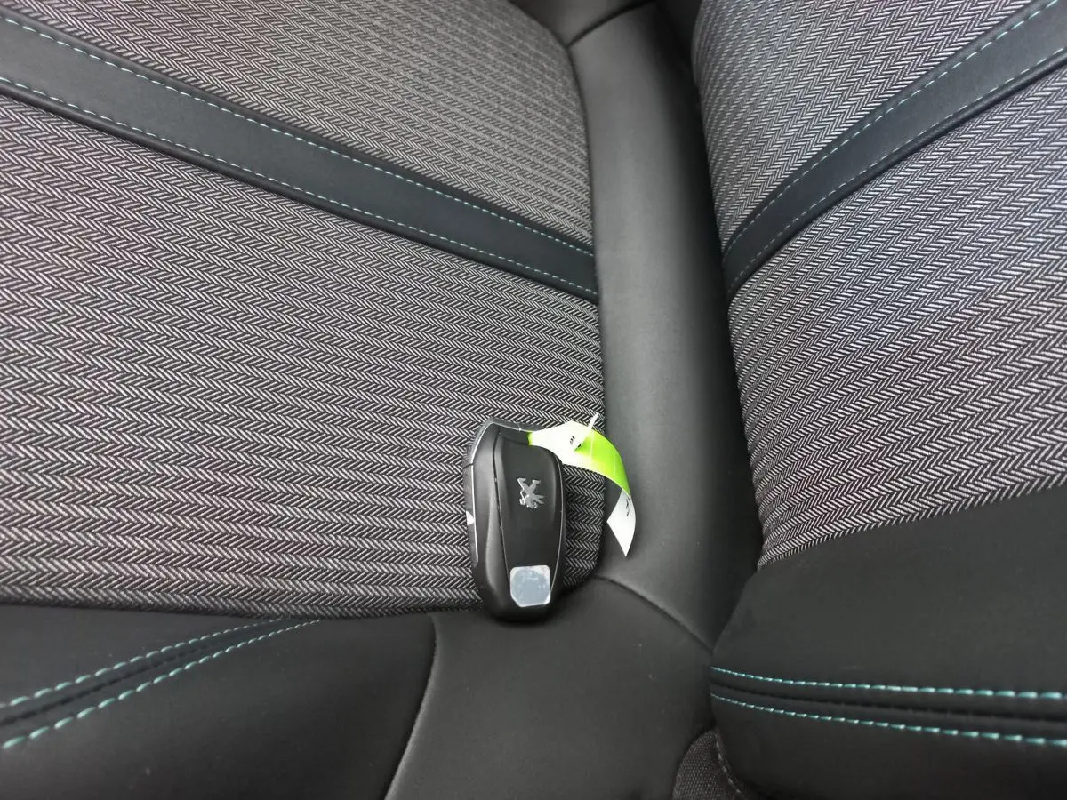 Clé Peugeot posée sur un siège tissu gris foncé avec surpiqûres bleues, intérieur d’un 5008 2021.