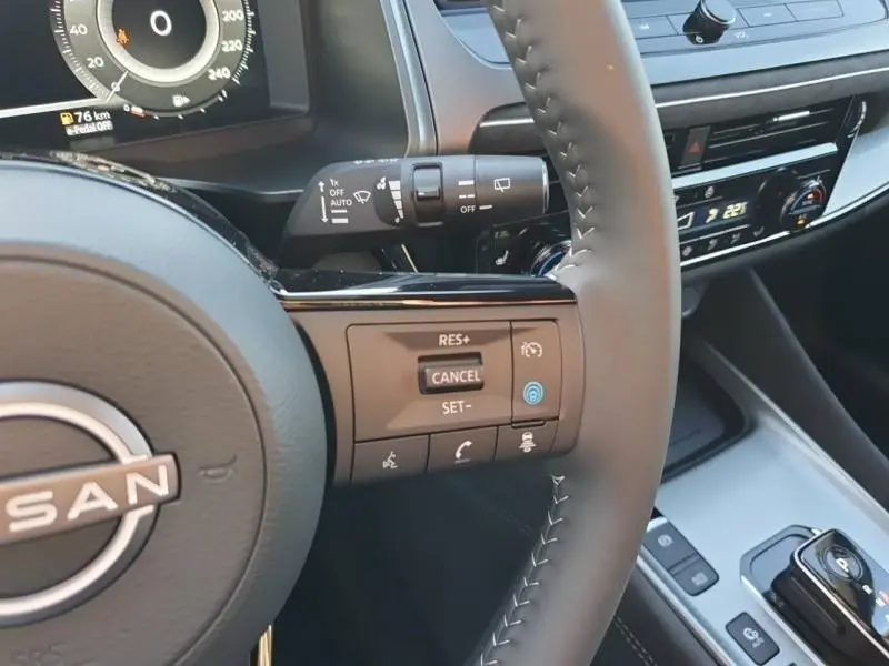 Vue rapprochée du volant noir du Nissan Qashqai 2025 avec commandes multifonctions et tableau de bord digital partiel.