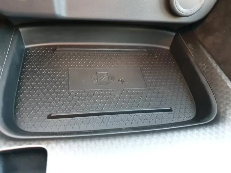 Gros plan sur le chargeur sans fil noir intégré dans la console centrale du Nissan Qashqai Hybrid e-POWER 2025.