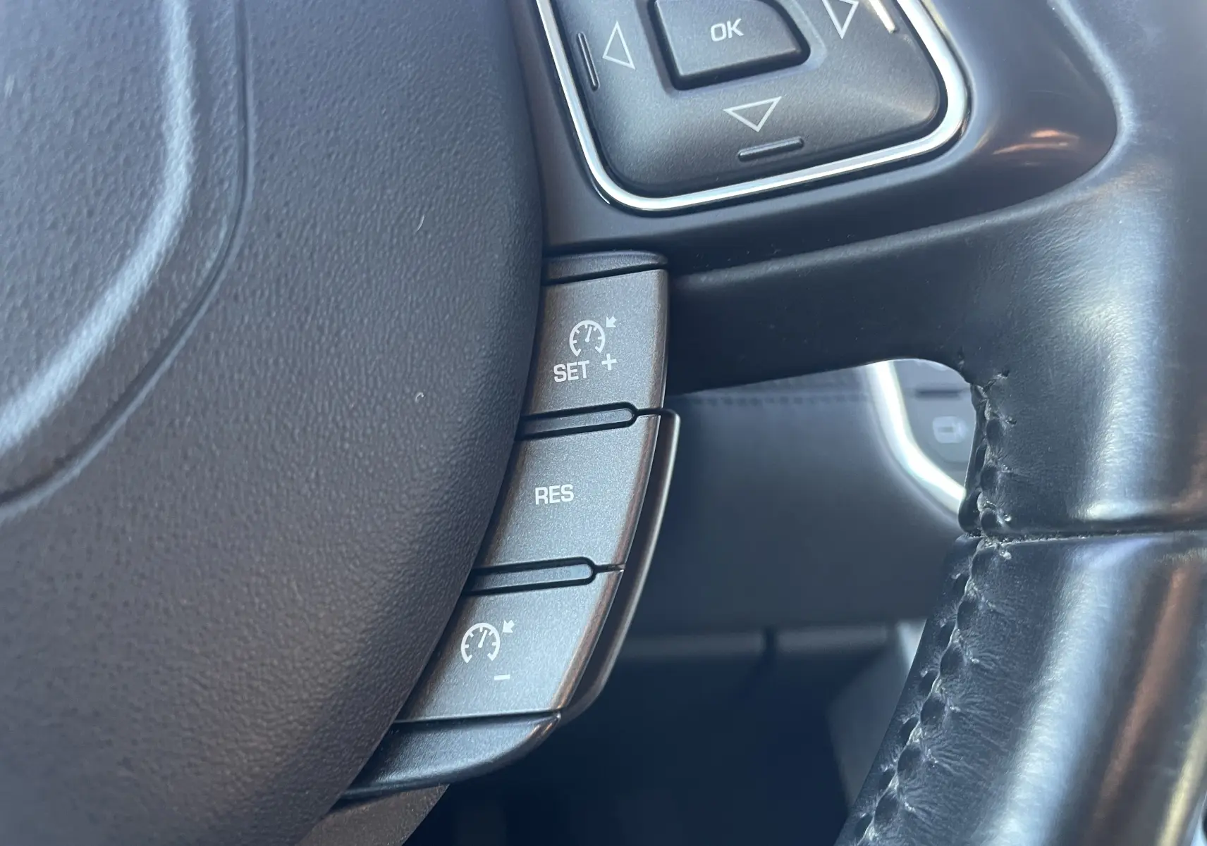Gros plan sur la partie gauche du volant en cuir noir du Range Rover Evoque 2016, avec commandes de régulateur de vitesse.