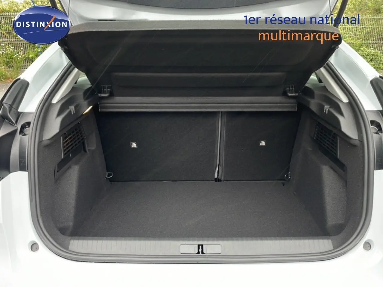 Coffre ouvert vu de l'arrière d'une Citroën C4 blanc métal, montrant un espace de chargement propre et spacieux.
