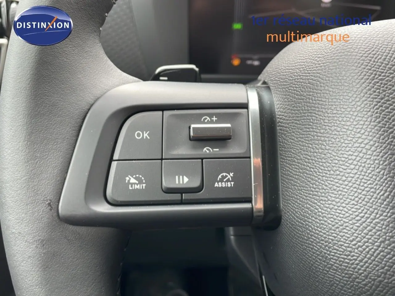 Gros plan sur les commandes au volant à gauche du Citroën C4 blanc métal, avec boutons de limitation et assistance.