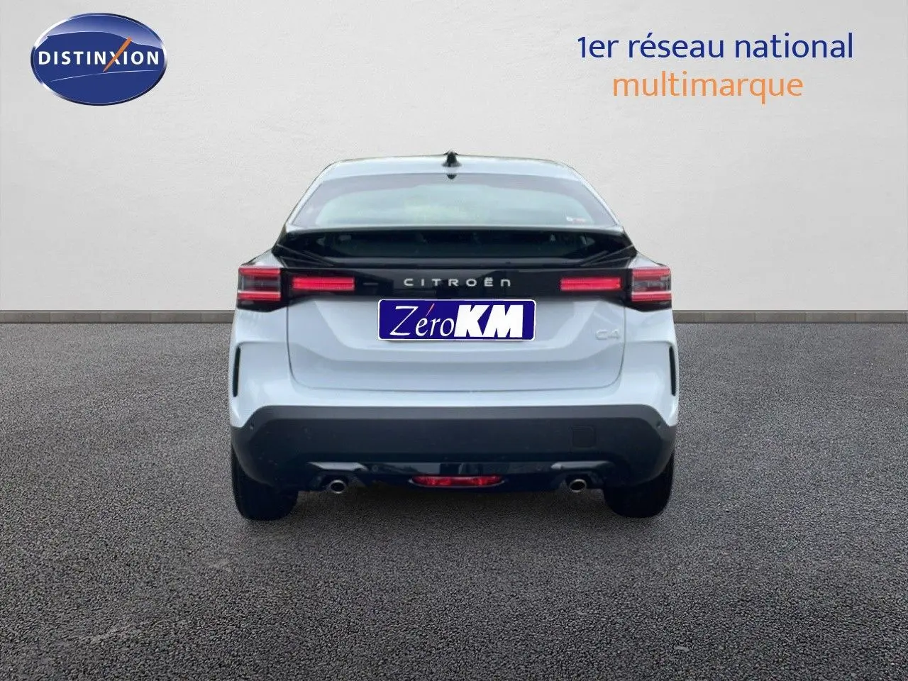 Vue arrière d'une Citroën C4 blanche métallisée avec bande noire et feux arrière LED allumés.