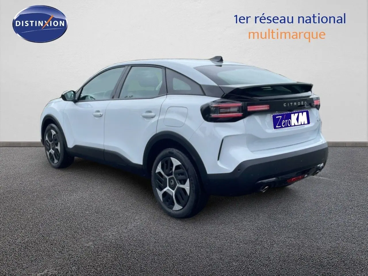 Vue 3/4 arrière droite d'une Citroën C4 blanche métal avec toit noir et feux arrière horizontaux LED.