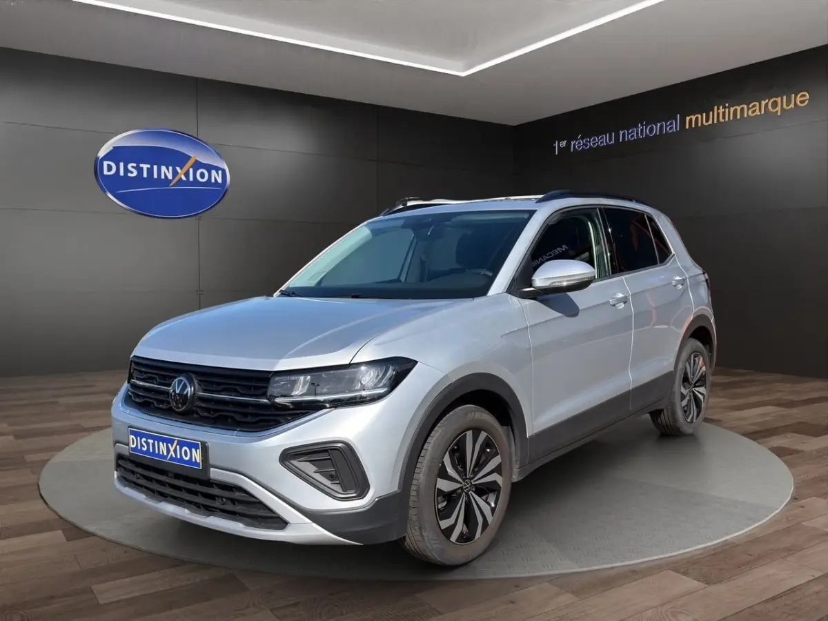 Volkswagen T-Cross gris clair en 3/4 avant droit, avec jantes alliage et calandre noire distinctive.