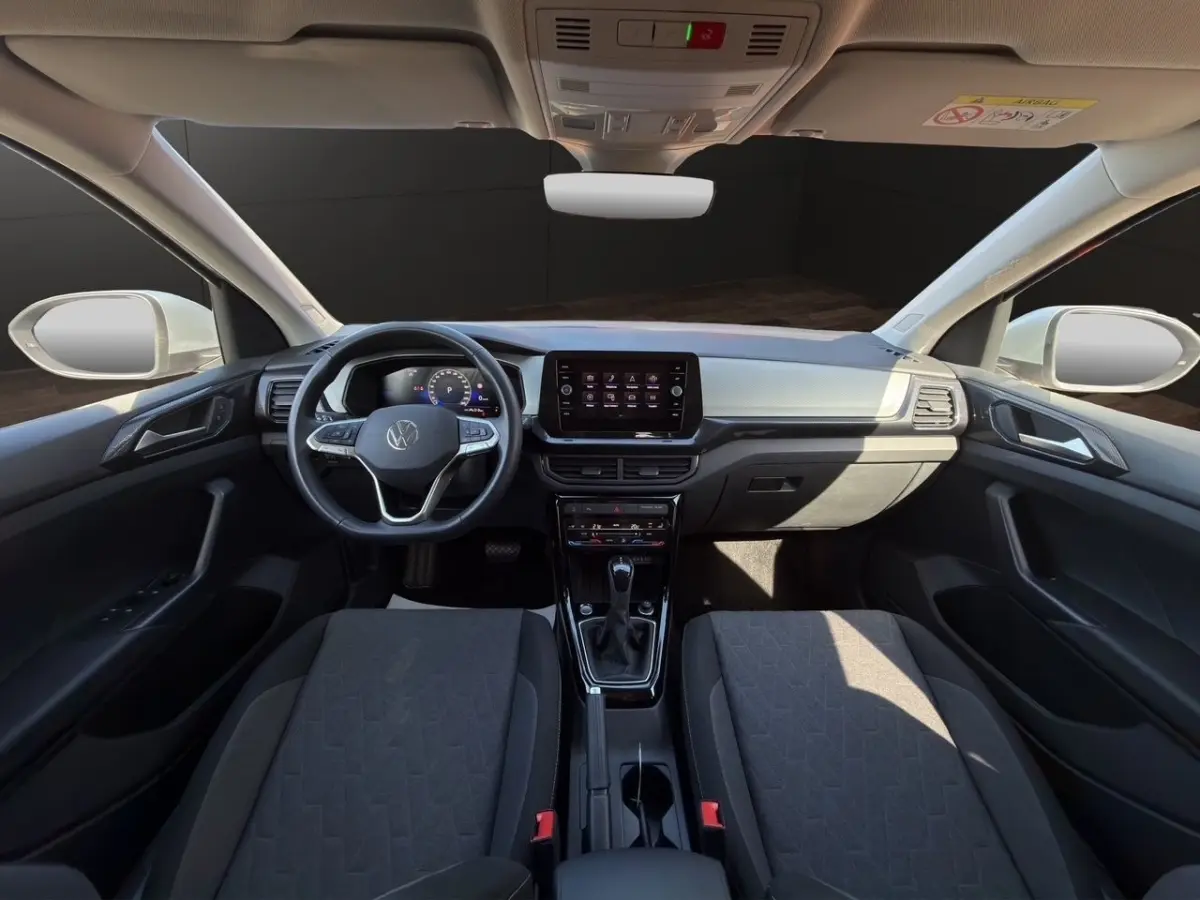 Vue intérieure frontale du tableau de bord et volant cuir alu du Volkswagen T-Cross 2025 avec écran tactile central.