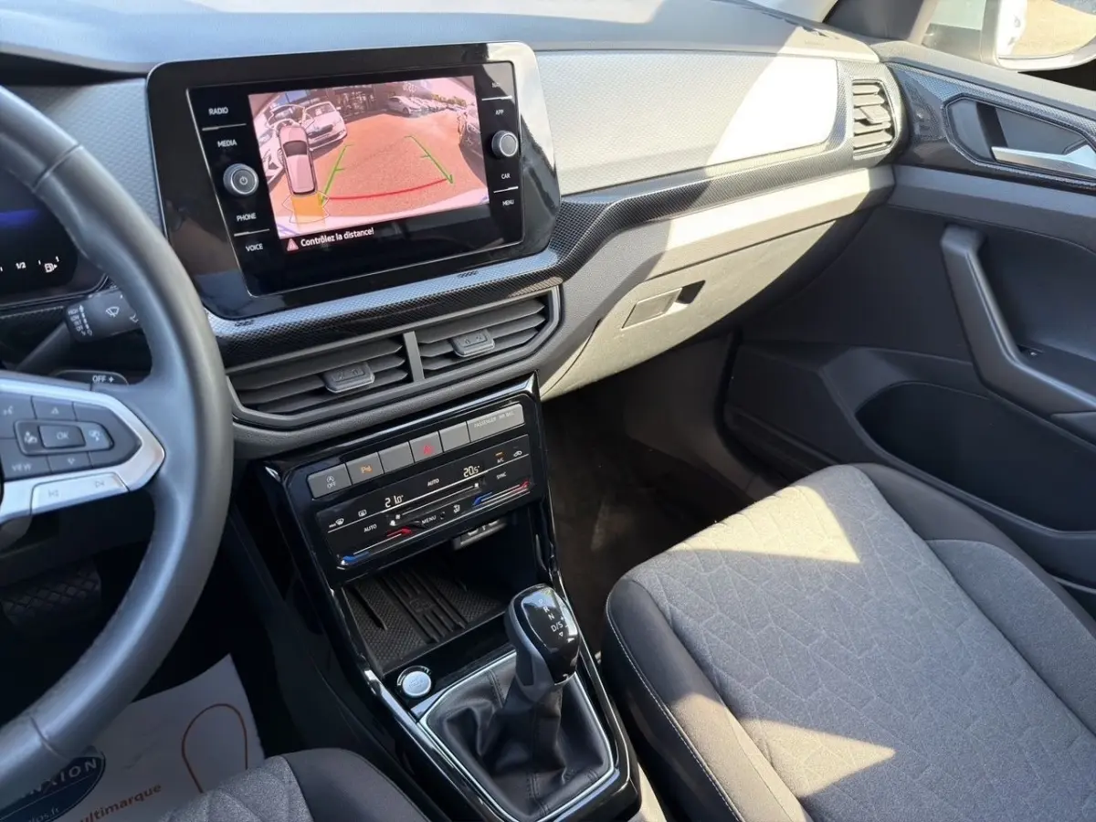 Vue intérieure côté passager du Volkswagen T-Cross gris clair 2025, avec écran tactile affichant la caméra de recul.