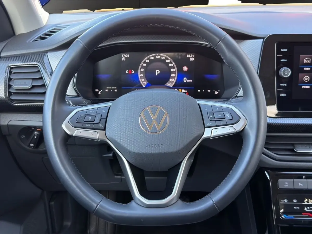Vue rapprochée du volant cuir noir Volkswagen T-Cross 2025 avec tableau de bord numérique et écran tactile central.