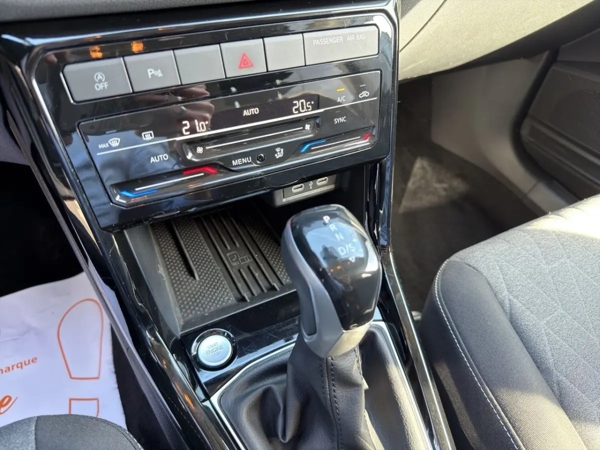 Gros plan sur la console centrale du Volkswagen T-Cross 2025, avec levier de boîte auto et commandes climatisation tactile.