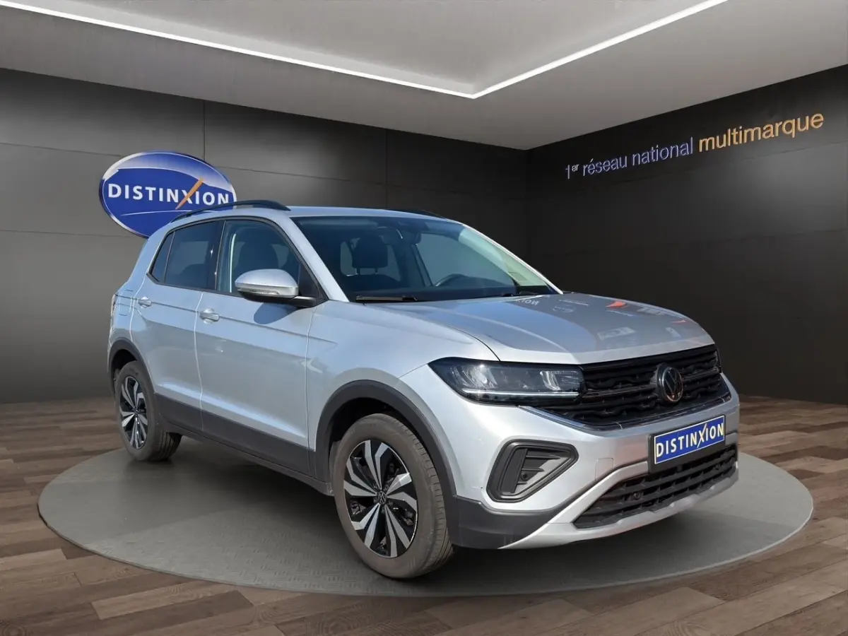 Volkswagen T-Cross gris clair vue 3/4 avant droit, avec calandre noire et jantes alliage distinctives.