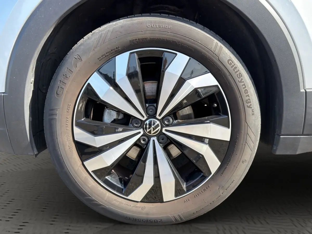 Gros plan sur la roue avant droite du Volkswagen T-Cross gris clair avec jante alliage bicolore distinctive.