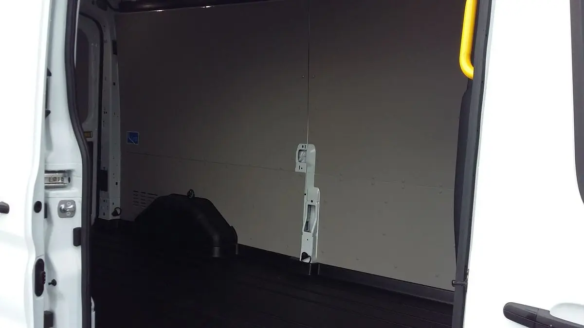 Vue intérieure côté gauche du fourgon Ford Transit blanc glacier, montrant l'espace de chargement vide et les parois claires.