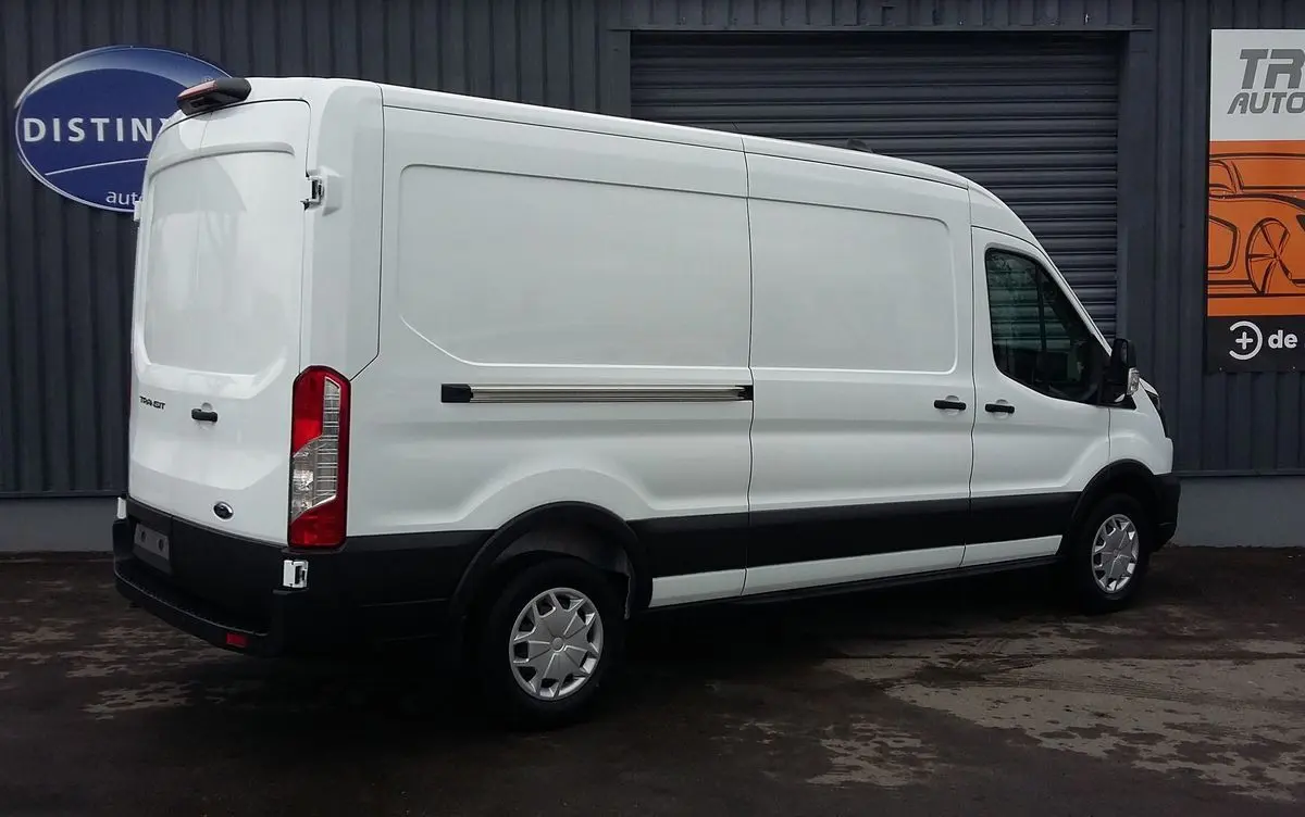 Fourgon Ford Transit blanc glacier vu en 3/4 arrière côté gauche, avec protections noires et jantes acier.