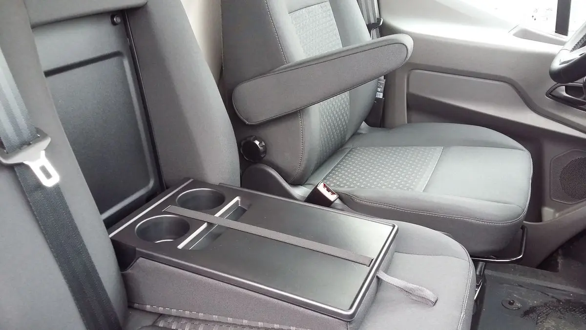 Vue rapprochée de l'intérieur côté passager du Ford Transit Fourgon 2022, sièges gris avec accoudoir et porte-gobelets.