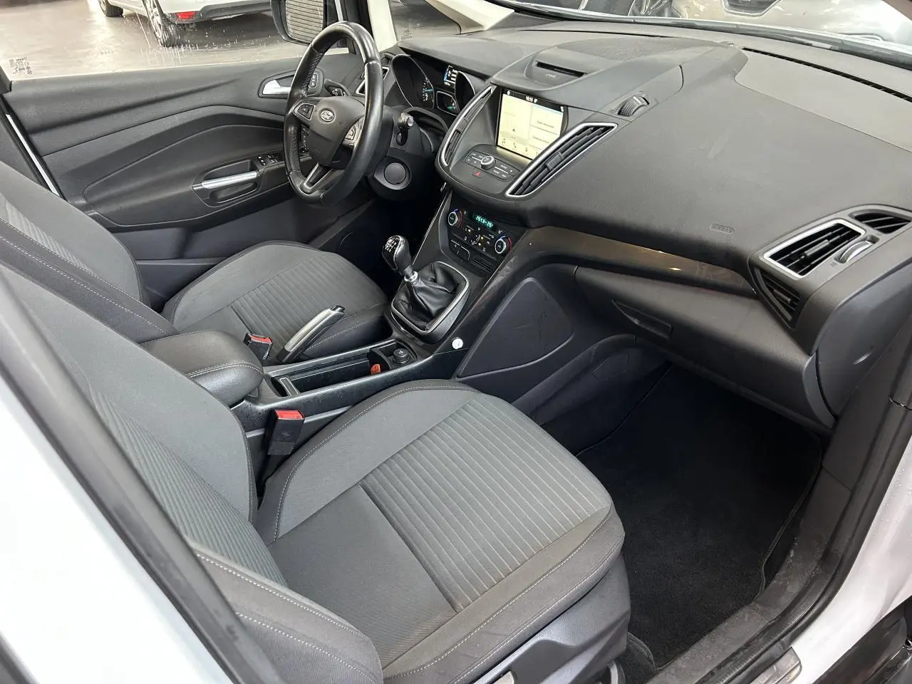 Vue intérieure côté conducteur du Ford C-MAX blanc 2018, avec tableau de bord et écran tactile SYNC 3 visible.