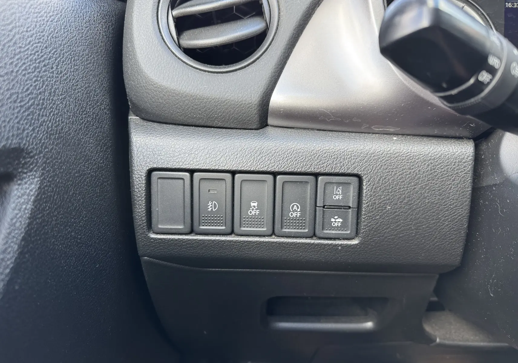 Gros plan sur les commandes noires à gauche du volant dans l'habitacle du Suzuki Vitara blanc 2023 hybride.