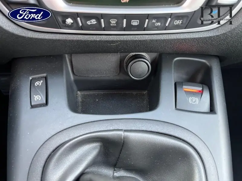 Gros plan sur la console centrale noire étoilé du Renault Grand Scenic 2012 avec frein à main électrique et commandes variées.