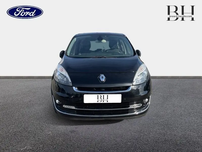 Vue frontale d'un Renault Grand Scenic noir étoilé avec phares allongés et calandre chromée visible.