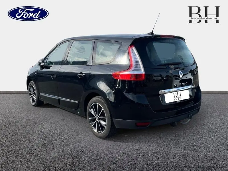 Renault Grand Scenic noir étoilé vu en 3/4 arrière droit, avec jantes alu 17 pouces et barres de toit visibles.