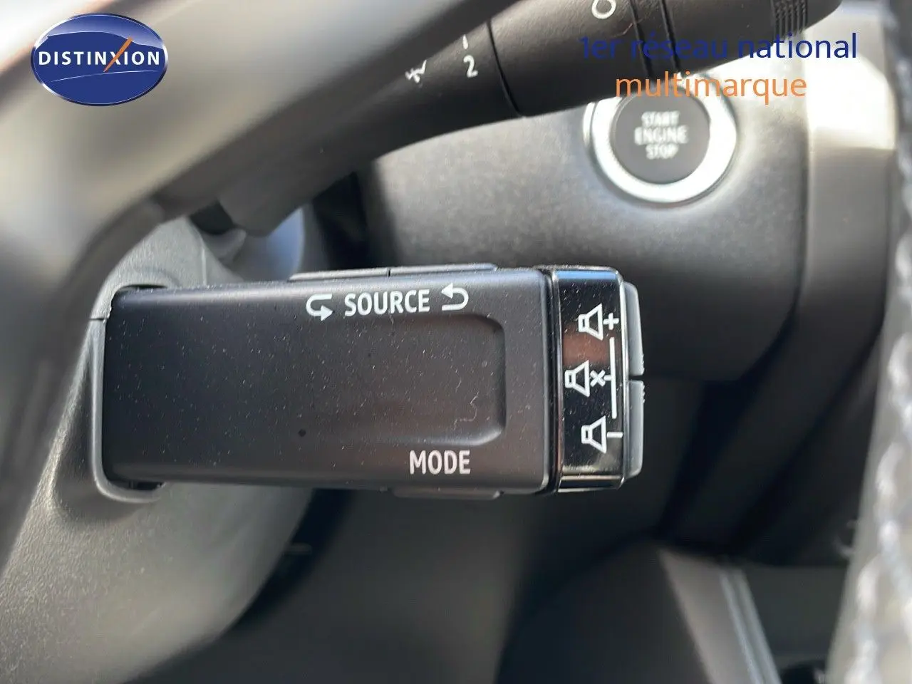 Gros plan sur la commande au volant du Renault Captur E-Tech hybride 2025, avec bouton source et mode visibles.