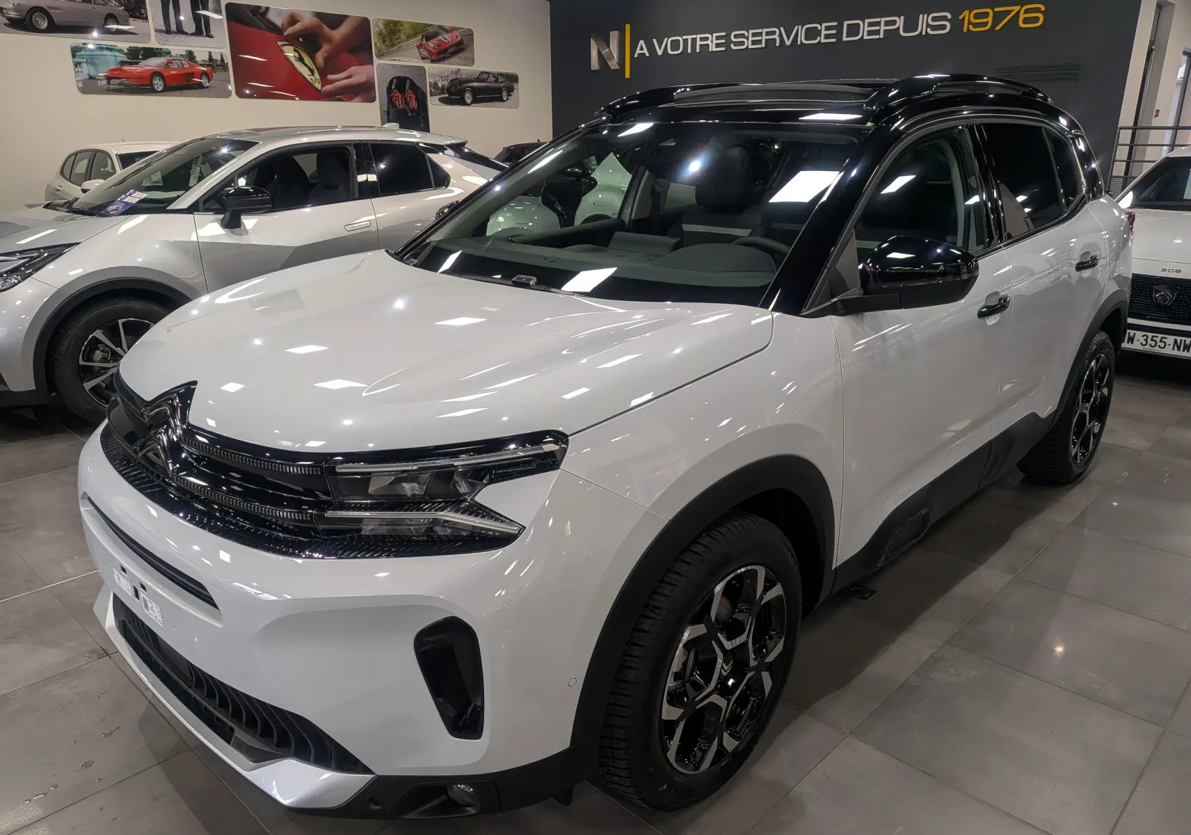 Citroën C5 Aircross hybride blanc Okénite avec toit noir, vue 3/4 avant droit en showroom lumineux.