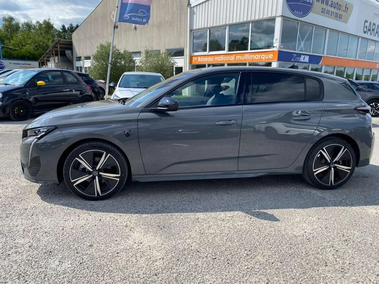 Profil côté gauche d'une Peugeot 308 GT gris selenium 2025 avec jantes noires et détails sportifs visibles.