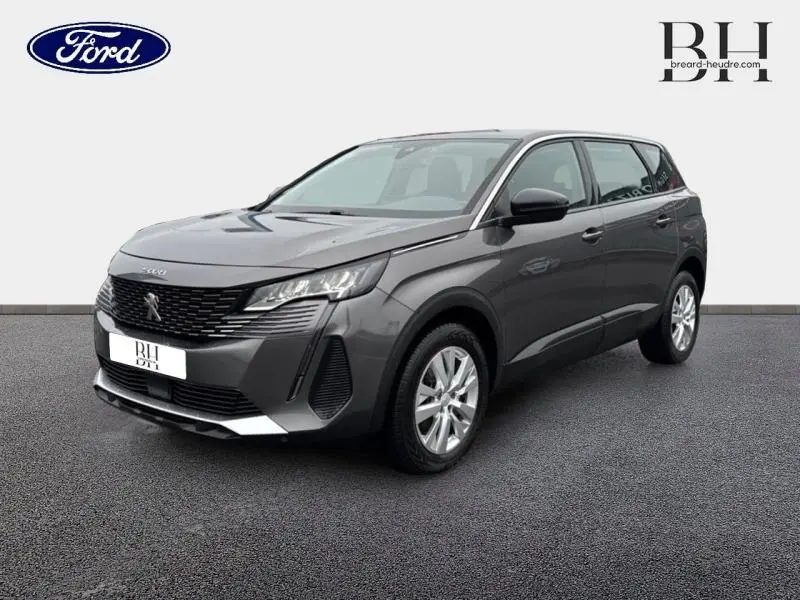 Peugeot 5008 gris Platinium vue 3/4 avant droit, avec calandre chromée et jantes alu visibles.