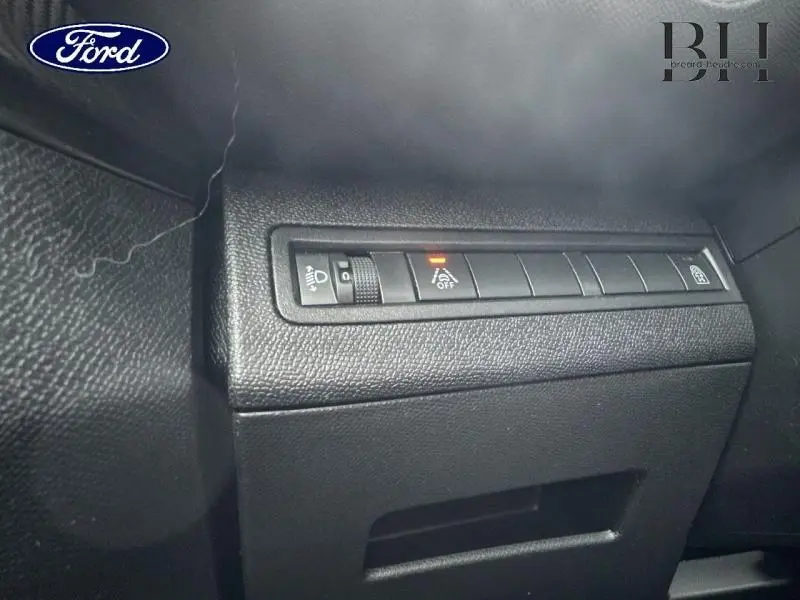 Détail des commandes d'assistance et réglage des phares sur un tableau de bord noir d'un Peugeot 5008 gris Platinium.