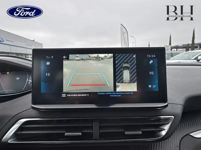 Vue intérieure du tableau de bord avec écran tactile affichant la caméra de recul du Peugeot 5008 gris Platinium, angle avant.