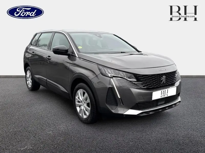 Peugeot 5008 gris Platinium en 3/4 avant droit, avec calandre noire et feux LED distinctifs.