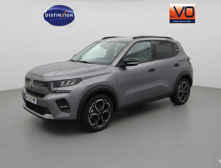 Vue 3/4 avant droit d'une Citroën C3 gris métallisé avec barres de toit et jantes alliage 17 pouces.