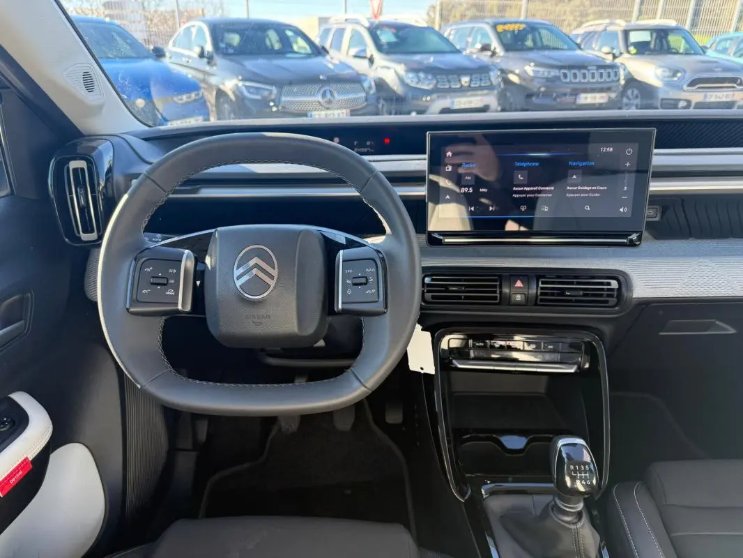 Vue intérieure centrée sur le volant et tableau de bord de la Citroën C3 gris 2025 avec écran tactile et boîte manuelle.