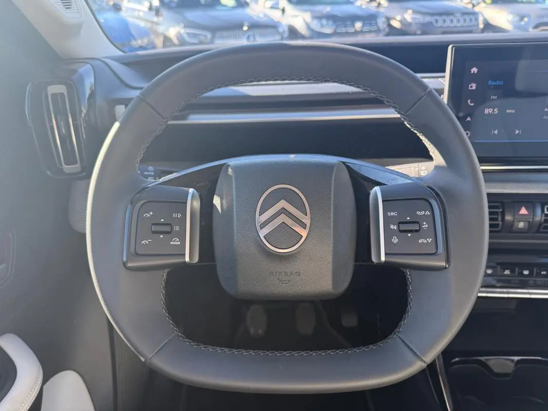 Vue rapprochée du volant noir de la Citroën C3 2025 avec commandes intégrées et tableau de bord numérique.