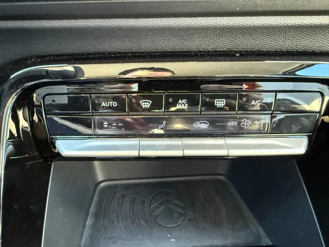 Vue rapprochée de la console centrale noire du Citroën C3 gris 2025, mettant en valeur les commandes de climatisation automatique.
