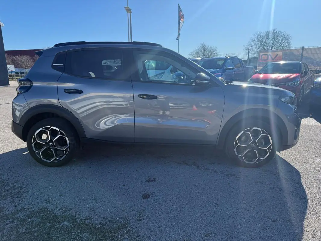 Profil côté gauche d'une Citroën C3 gris métallisé 2025 avec barres de toit et jantes alliage 17 pouces.