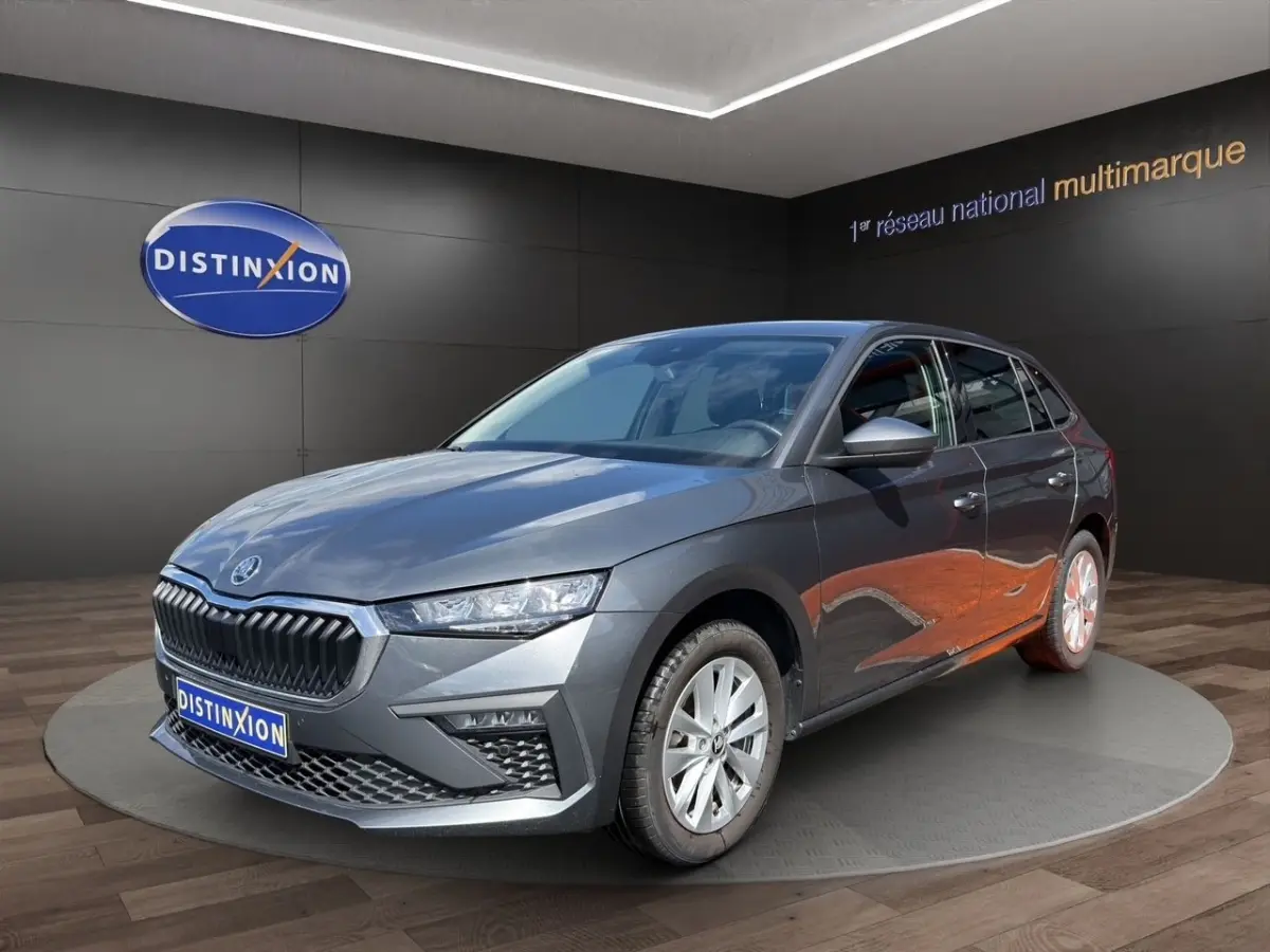 Vue 3/4 avant droite d'une Skoda Scala gris foncé exposée en showroom avec calandre noire distinctive.