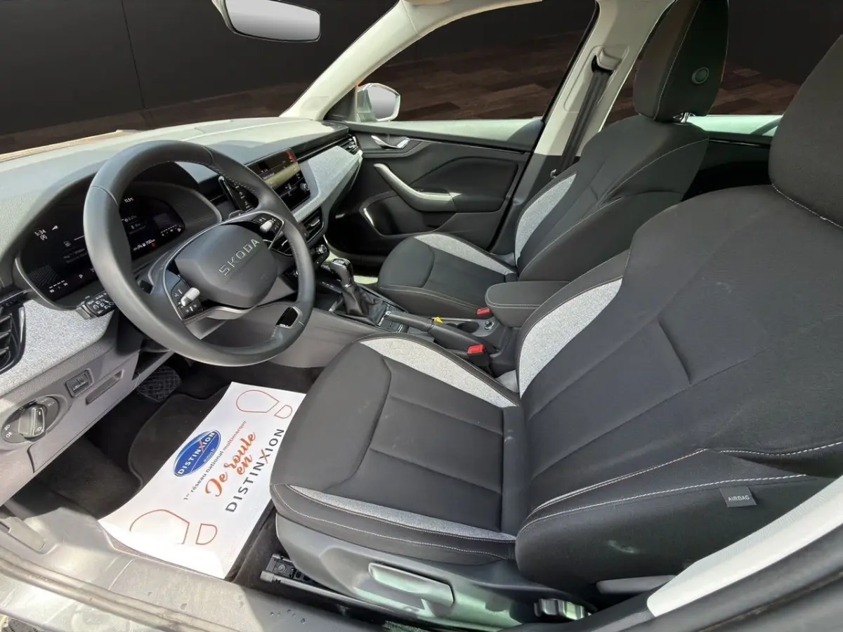 Vue intérieure côté conducteur de la Skoda Scala 2025 gris foncé, avec sièges bicolores et tableau de bord digital.