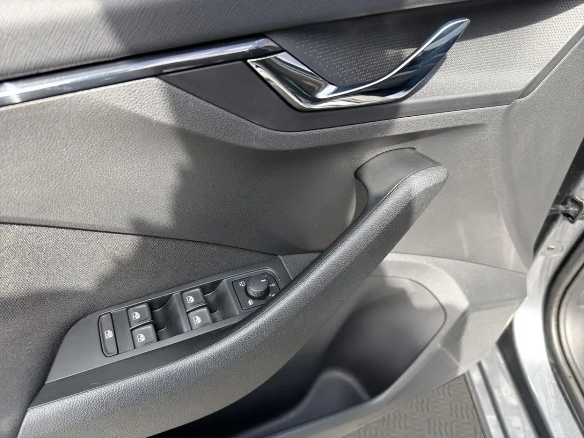 Vue rapprochée de la porte côté conducteur d’une Skoda Scala gris foncé, avec commandes électriques et poignée noire.