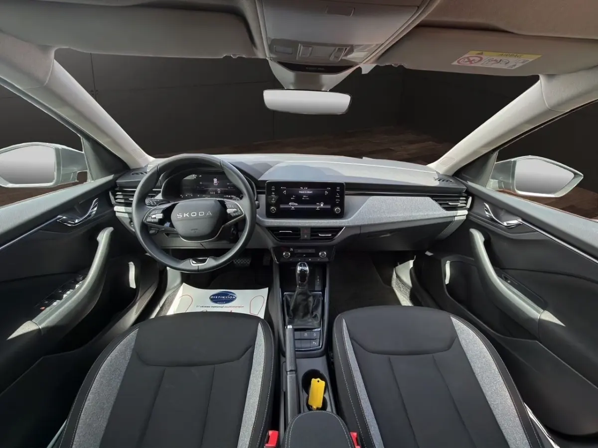 Vue intérieure avant de la Skoda Scala 2025, tableau de bord moderne gris et noir avec écran tactile central.