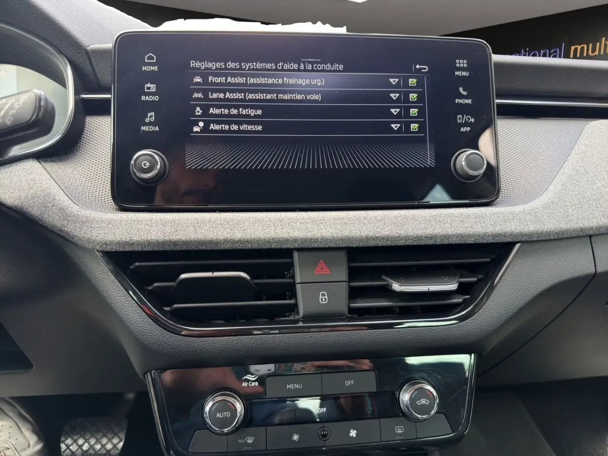 Vue rapprochée de l’écran tactile central et de la console de commande de la Skoda Scala 2025, affichant les réglages d’aide à la conduite.