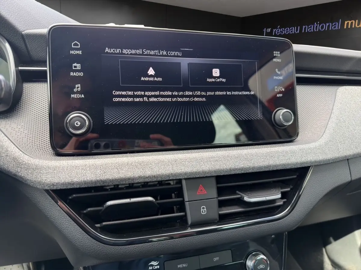 Vue rapprochée de l’écran tactile central et des commandes de ventilation du tableau de bord gris clair d’une Skoda Scala 2025.
