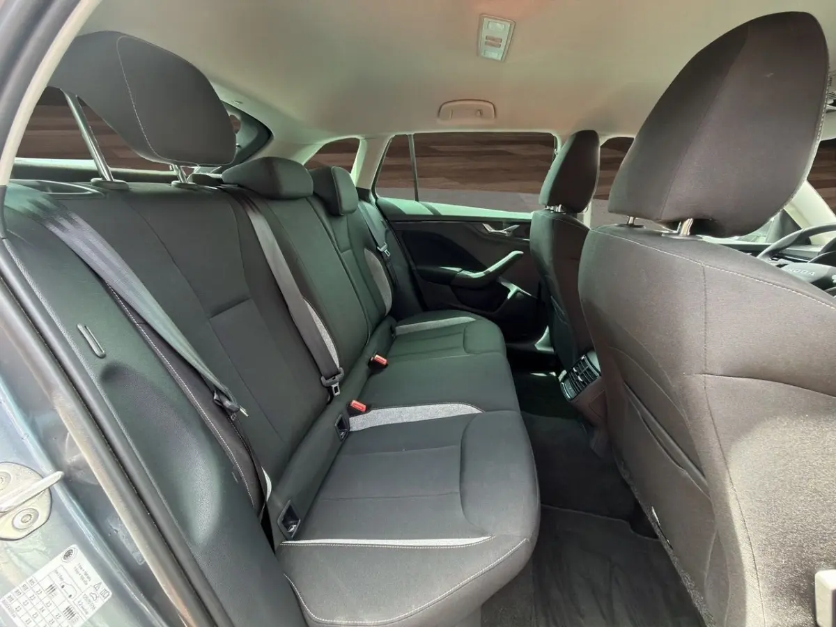 Vue intérieure arrière de la Skoda Scala gris foncé, montrant la banquette et les sièges avant en tissu noir.