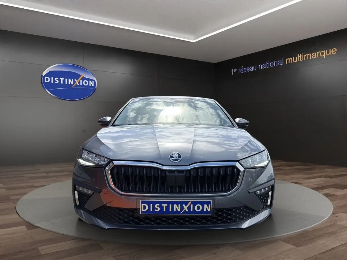 Vue frontale d'une Skoda Scala gris foncé avec calandre noire et phares LED allumés en showroom.