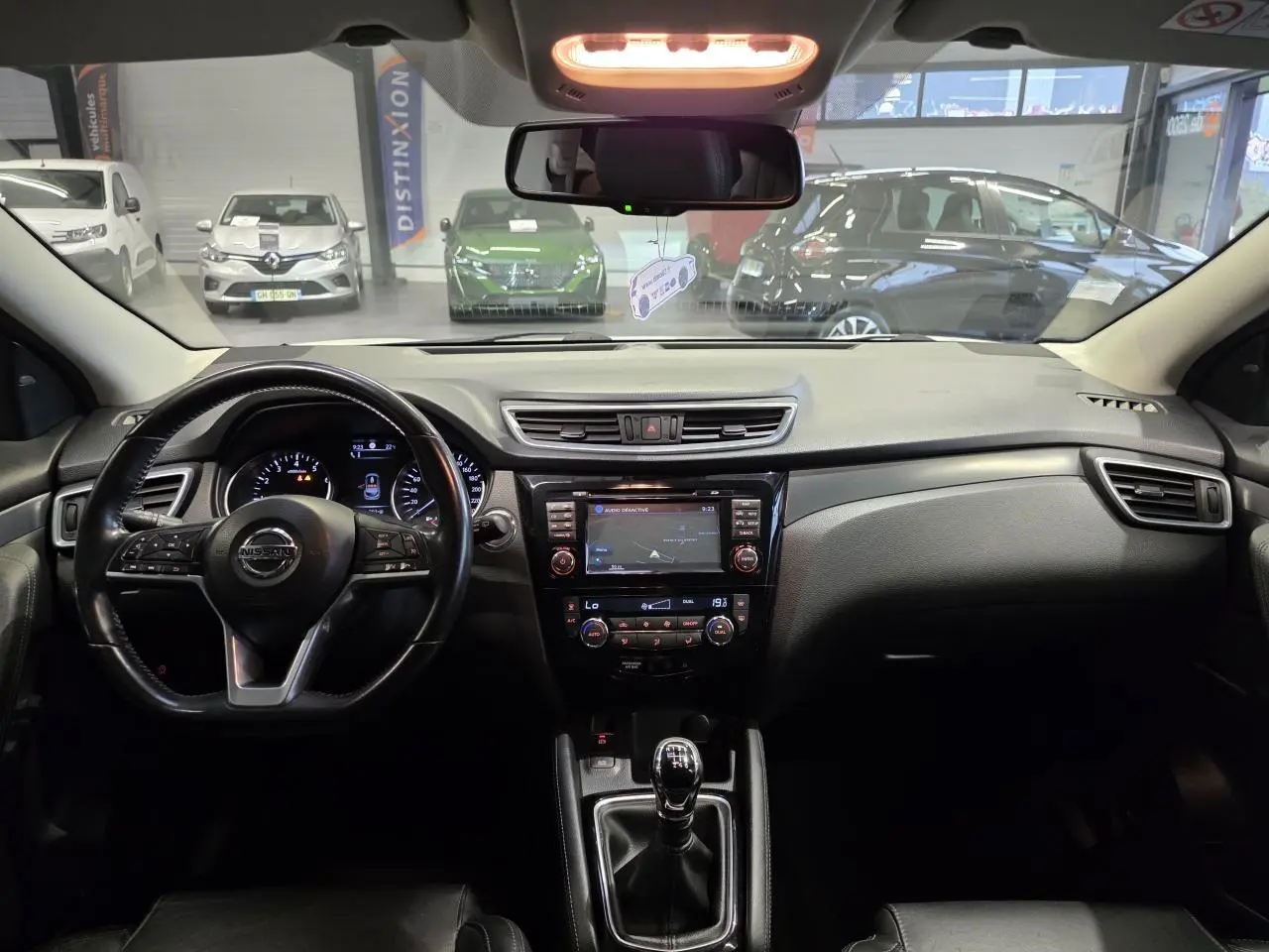 Vue intérieure avant du tableau de bord noir du Nissan Qashqai 1.2 DIG-T 2018 avec volant cuir et écran tactile central.